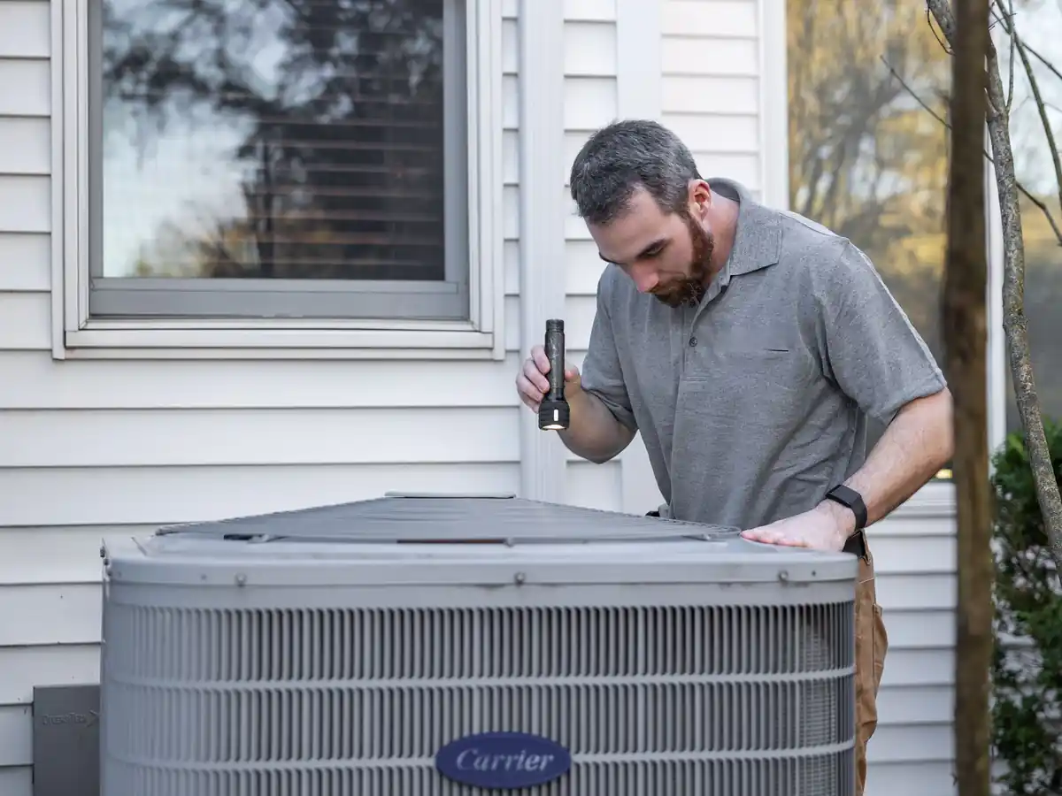 HVAC technician inspecting an outdoor air conditioner at a home in Adelphi, MD
