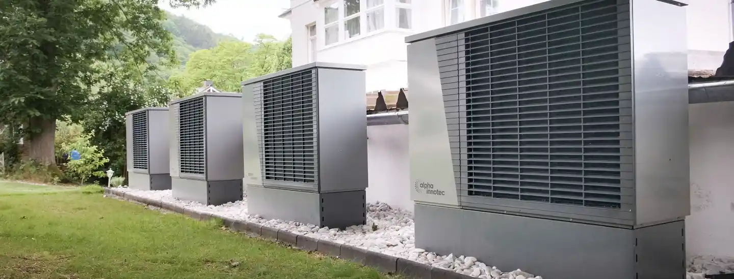 Row of outdoor heat pumps beside a building