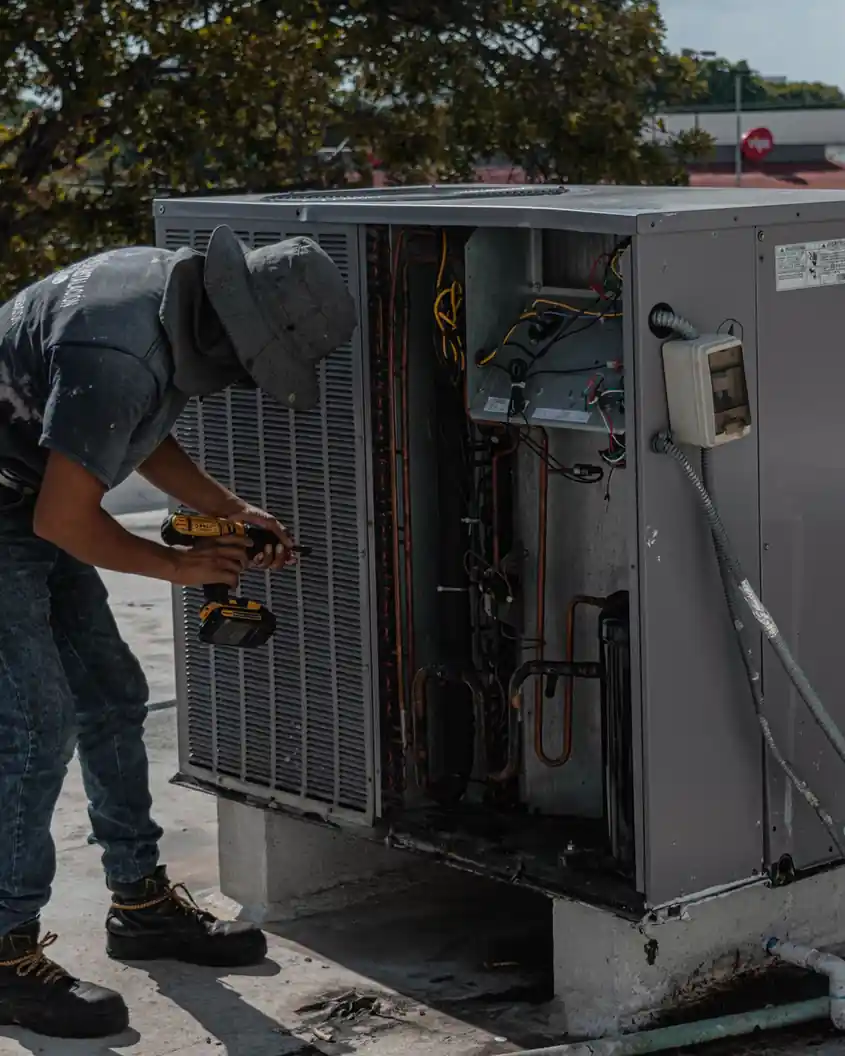 Technician repairing an outdoor air conditioning unit on a rooftop