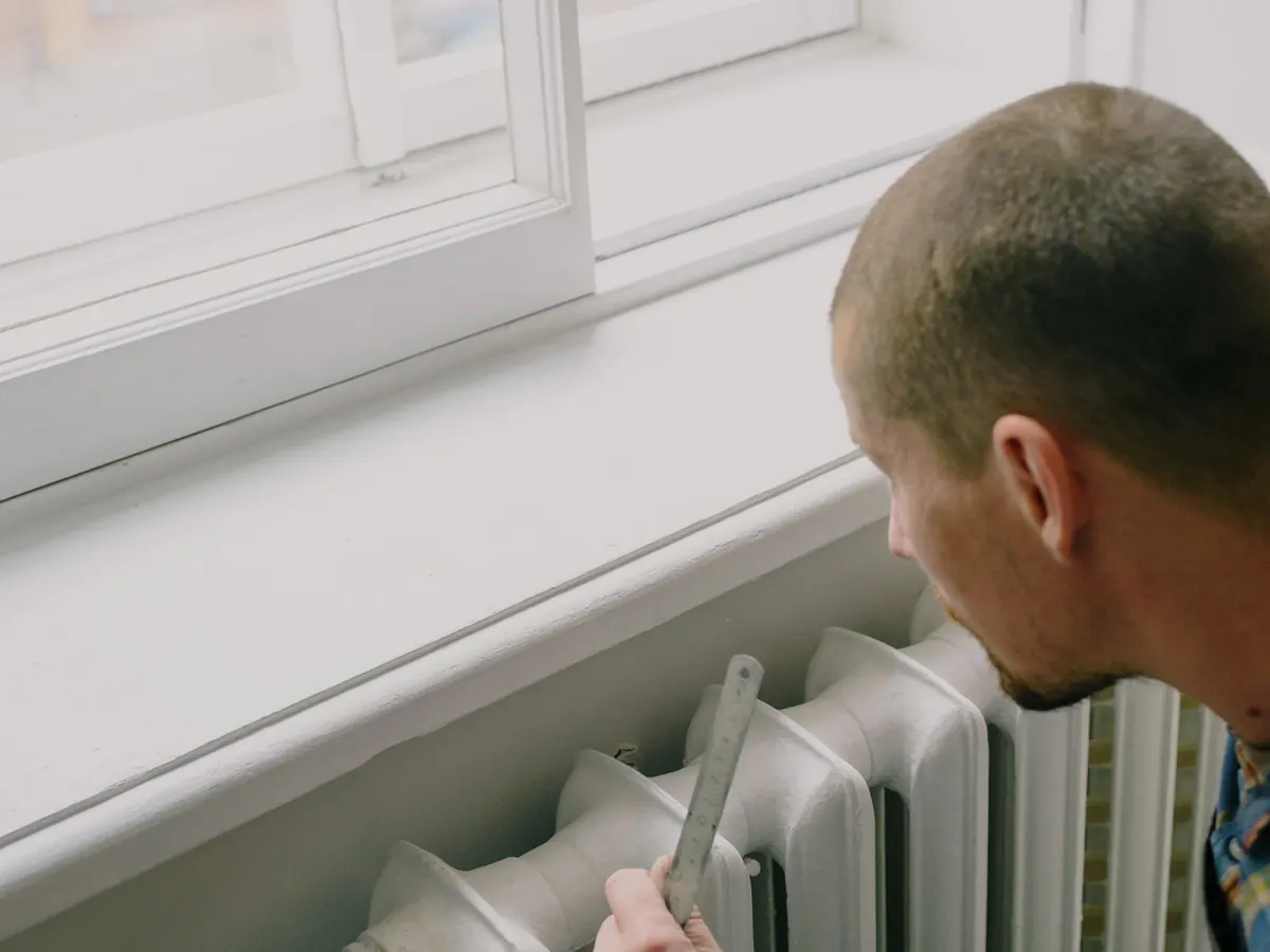 Worker fitting a radiator beside a window