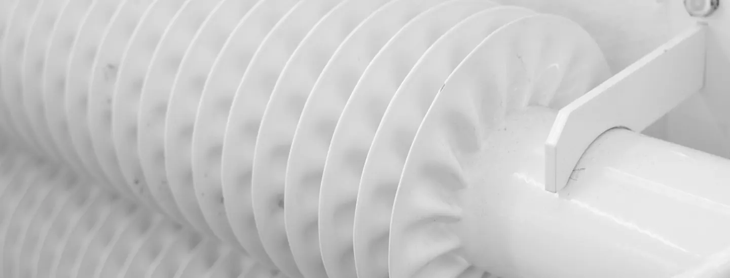 Finned white heating pipe in a bright room