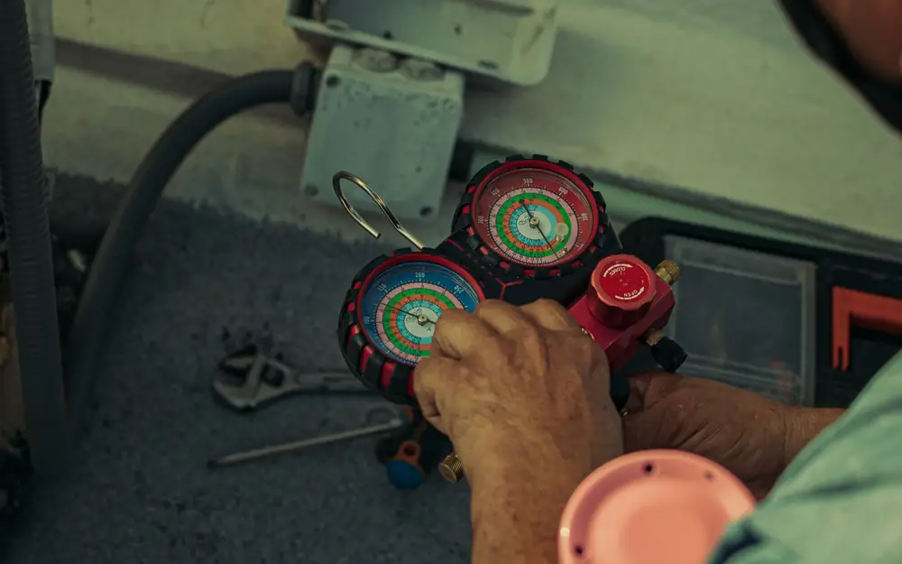 Technician reading manifold gauges during HVAC maintenance