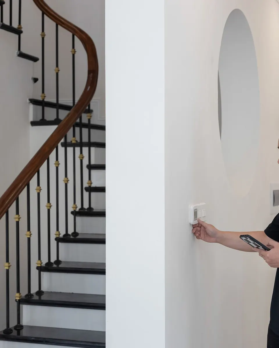 Technician adjusting a wall thermostat in a home