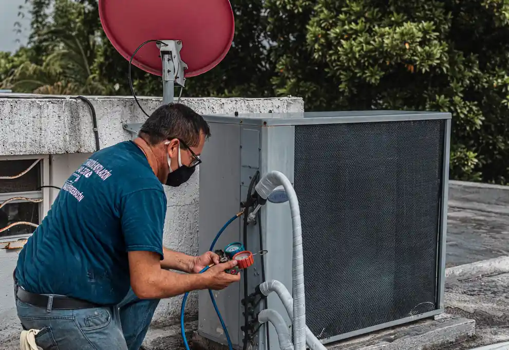 Technician checking an outdoor air conditioning unit with a manifold gauge