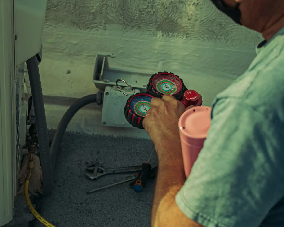 Technician checking an outdoor HVAC system with a manifold gauge