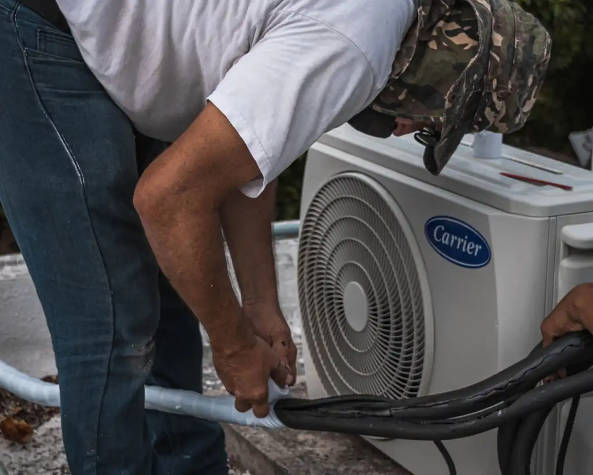 Technician maintaining the hose connections of an outdoor air conditioning unit