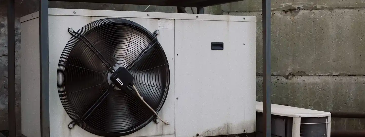 Outdoor air conditioner units on a metal platform beside a modern building