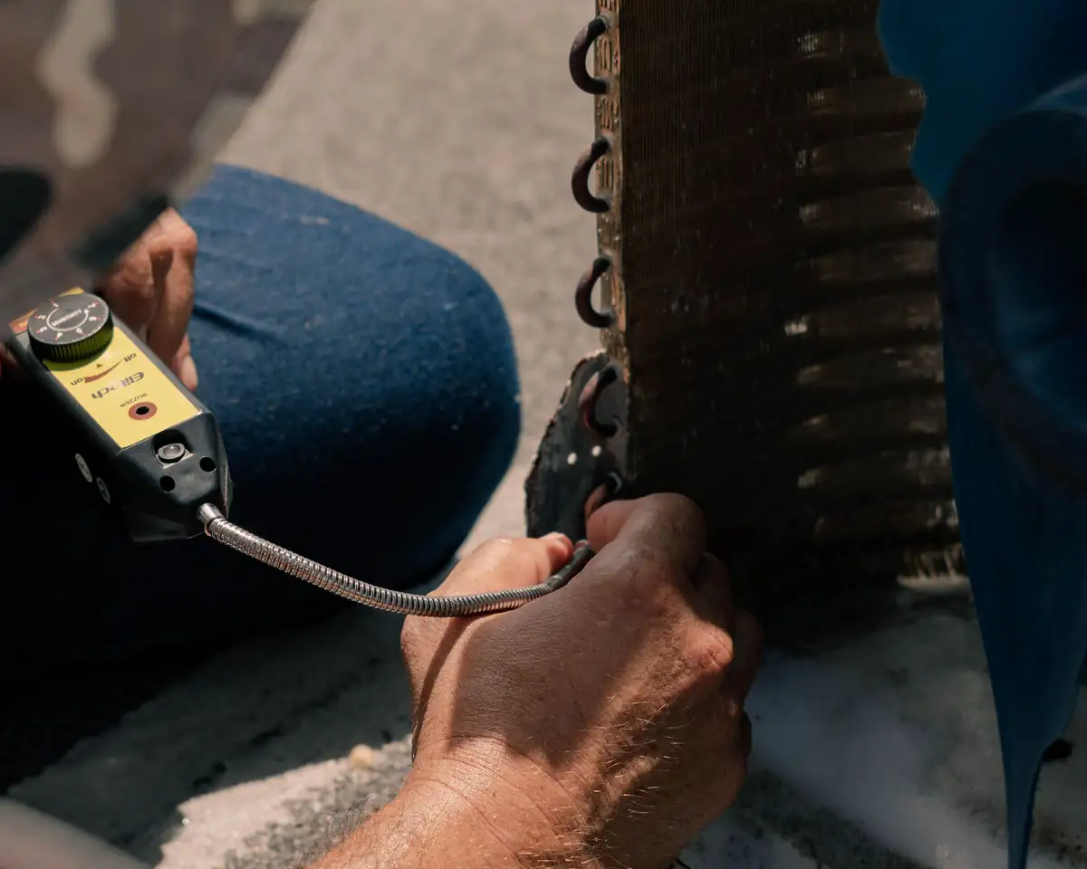 Technician repairing an air conditioner with a testing tool