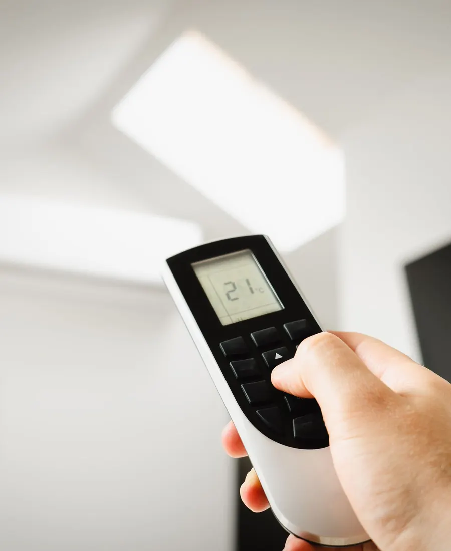 Hand holding a remote control to adjust the air conditioner