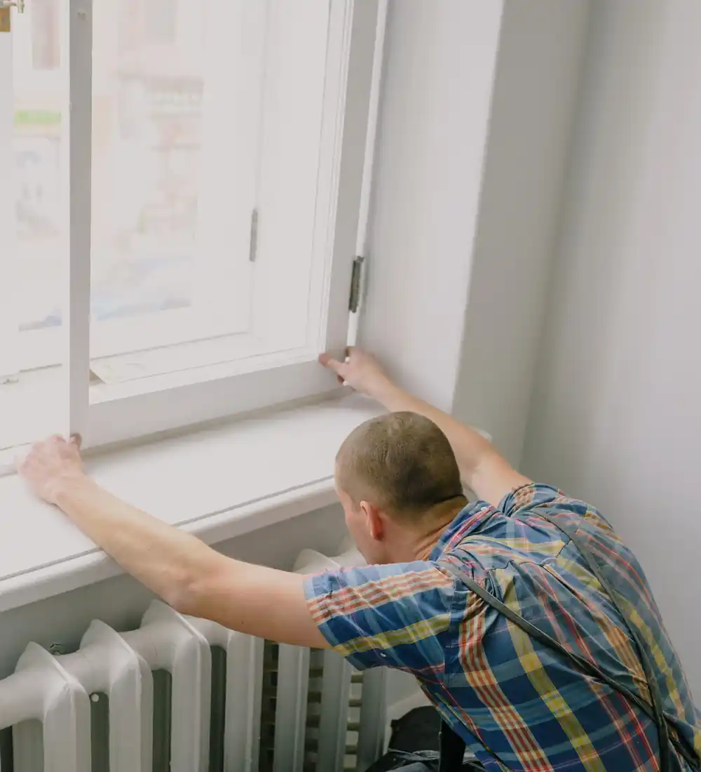 Fitter installing a window above a radiator