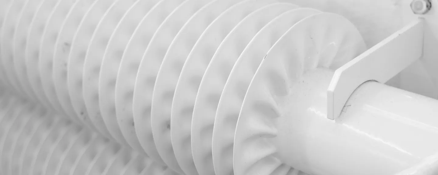 Finned white heating pipe in a bright room