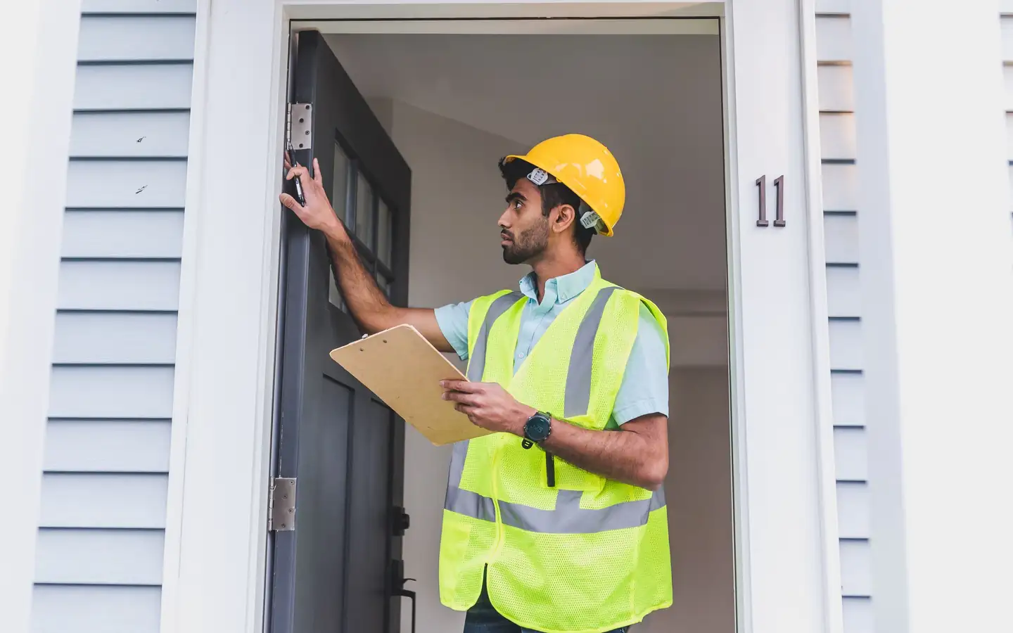 Inspector checking a doorframe with a clipboard