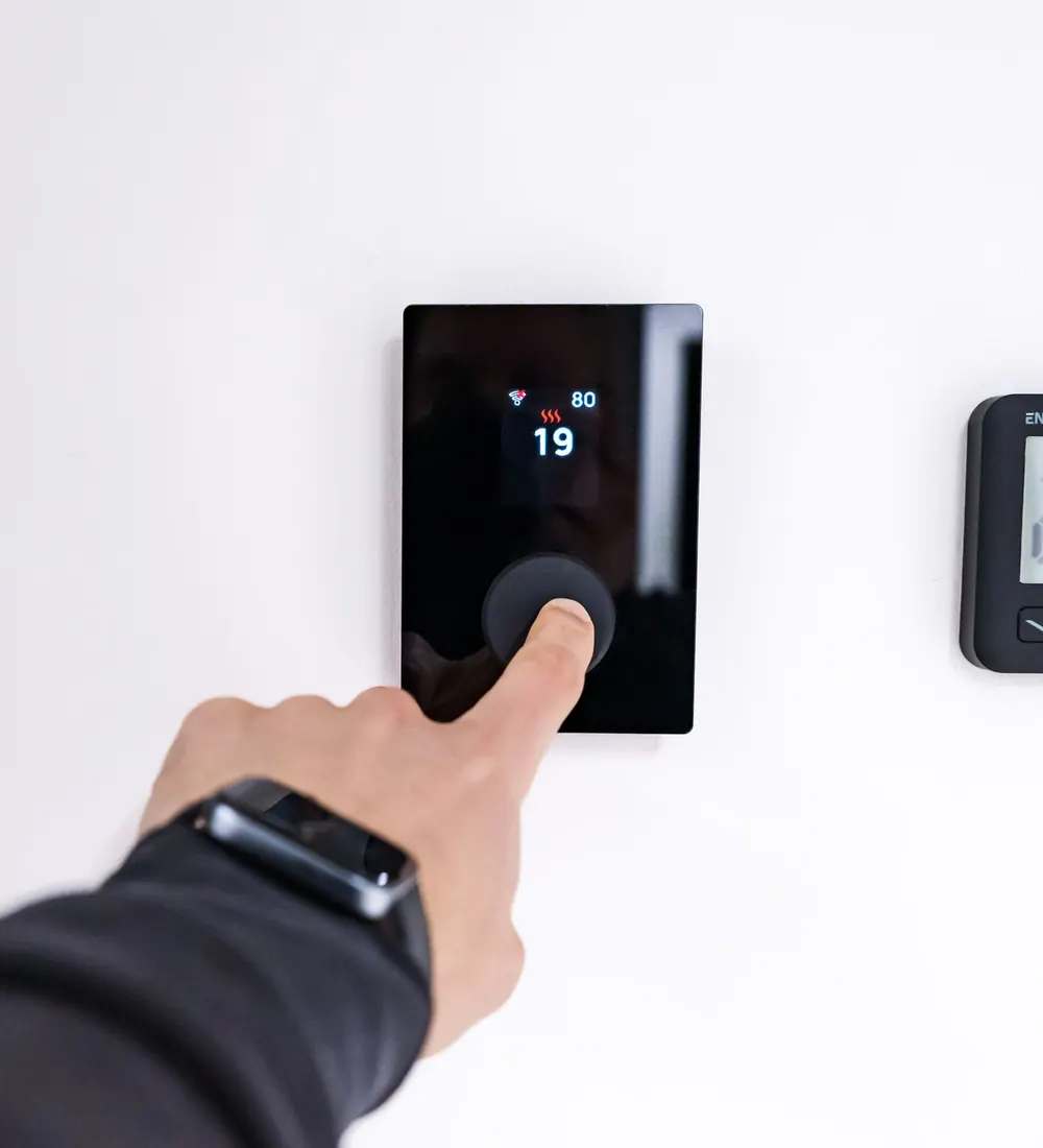 Hand adjusting a digital wall thermostat